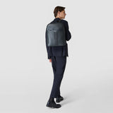 Rear view — BACKPACK IN CACHEMIRE LEATHER AND MOSAICO, worn by a man in a dark suit, navy supple leather with vertical Mosaico detail, sleek office-ready design.