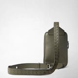 Front view: SLING BACKPACK IN CACHEMIRE LEATHER AND MOSAICO stands upright, olive-green grained cachemire leather with a Mosaico-embossed shoulder strap against a light neutral background.