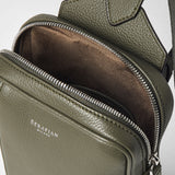 Detail view: SLING BACKPACK IN CACHEMIRE LEATHER AND MOSAICO shows the front-opened main compartment of olive-green pebbled cachemire leather, brown suede lining, silver zipper, and 'SERAPIAN MILANO' embossing.