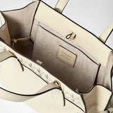 Detail view, SMALL MARO BAG IN CACHEMIRE LEATHER AND MOSAICO — open cream-colored interior with suede-like lining, slip pocket, side knots and embossed label 'SERAPIAN MADE IN ITALY'.