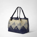 Frontal view: SMALL SECRET TOTE BAG IN DENIM AND RAFFIA stands on a light background; navy blue jacquard denim with raffia texture, adjustable leather handles. Visible lettering: SERAPIAN.
