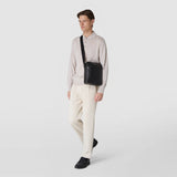 Front view: NORTH SOUTH CROSSBODY BAG IN EVOLUZIONE LEATHER worn diagonally across the chest; smooth black calfskin, rectangular shape, external zipper and adjustable black shoulder strap.