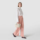 Frontal view: Model wears MINI SECRET BAG IN MOSAICO MESTIERI D'ARTE in Bokashi Cream, holding it by the short handle against a neutral light-gray studio background.