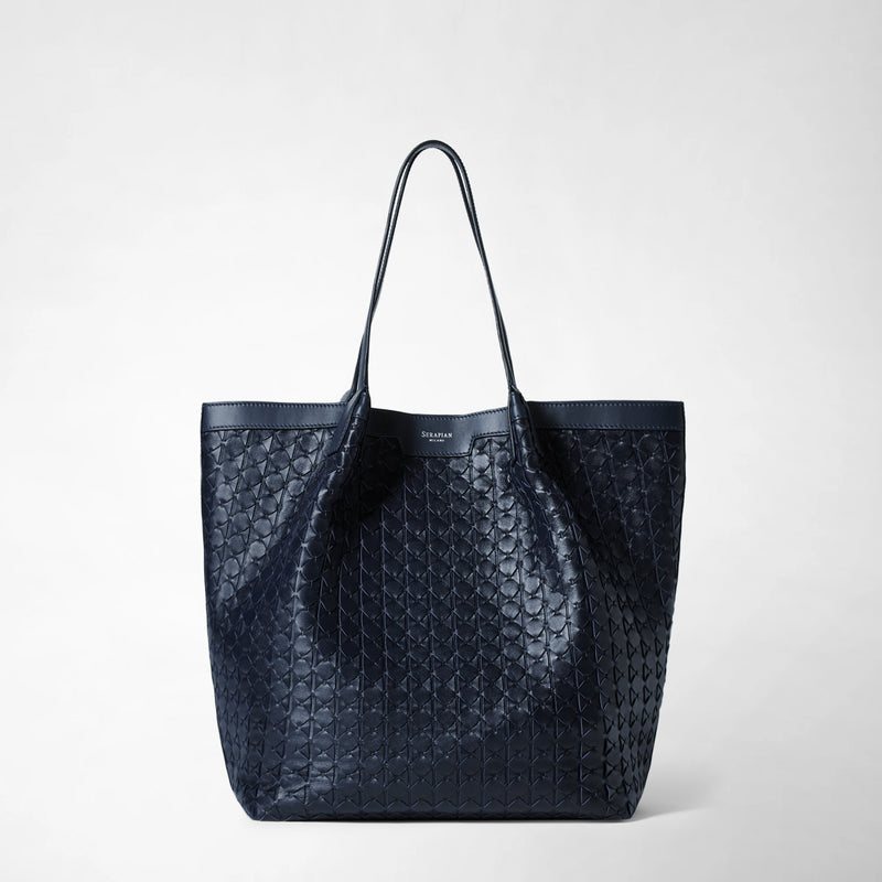 Frontal view: VERTICAL SECRET TOTE BAG IN MOSAICO displays a large navy blue tote bag with long handles and a geometric hand-woven leather pattern. Subtle branding is visible near the top.
