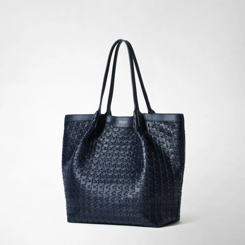 Frontal view: VERTICAL SECRET TOTE BAG IN MOSAICO shows a navy blue leather tote bag with a raised geometric woven pattern and double handles.