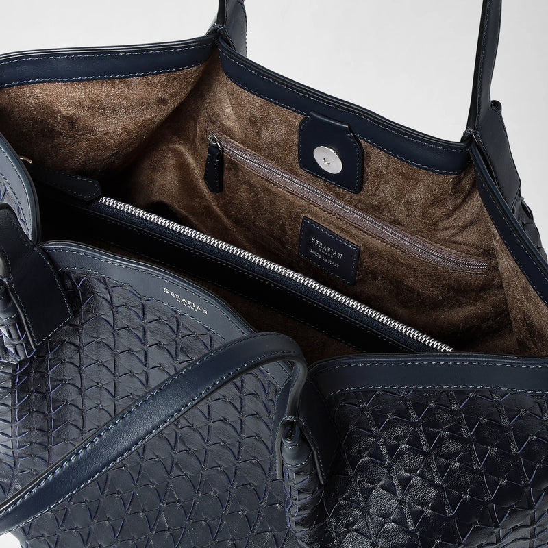 Detail view: VERTICAL SECRET TOTE BAG IN MOSAICO shows a close-up of the interior and top edge of a navy blue woven leather tote bag, revealing multiple compartments, a zipped pocket, brown suede lining, and &#39;SERAPIAN MILANO MADE IN ITALY&#39; printed inside.