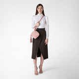 Frontal view: PETRA HANDBAG IN MOSAICO shown in blush pink nappa leather, worn crossbody by a woman dressed in a white blouse and dark skirt.