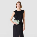 Frontal view: MINI SECRET CLUTCH BAG IN RIBBON MOSAICO held by model, aqua Ribbon Mosaico with three-dimensional woven texture, small decorative chains, compact clutch worn close to the body.