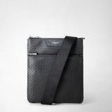 Front view: FLAT CROSSBODY BAG IN STEPAN, black flat bag with embossed S pattern, front zip pocket, adjustable shoulder strap draped diagonally on a light background; visible 'SERAPIAN MILANO' lettering.