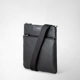 Front view: FLAT CROSSBODY BAG IN STEPAN, black with S-embossed surface, standing on a white background; adjustable wide shoulder strap draped over the front. Visible text: SERAPIAN MILANO.