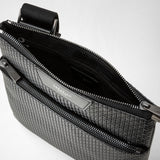 Close-up — FLAT CROSSBODY BAG IN STEPAN: open bag shows textured black Stepan material, two zippered pockets and strap attachment; interior leather with 'SERAPIAN' embossing visible.
